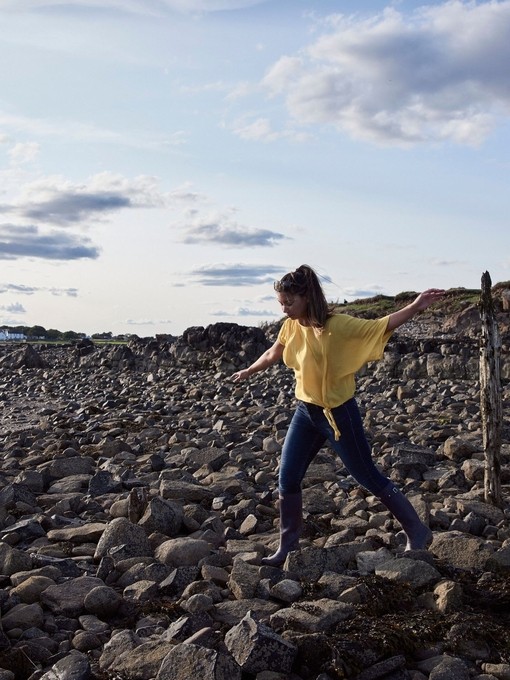 Woman balancing on rocks in between old stakes