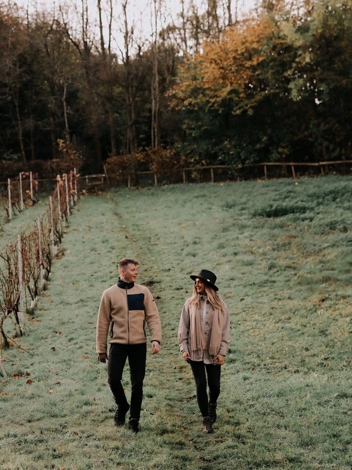 A man and woman walking in a vineyard