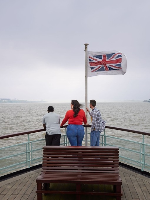 A group of friends, two men and a woman experience ferry ride across a city river.