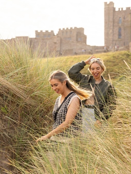 A couple walking in the sand dunes near Bamburgh Castle
