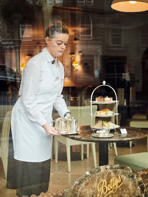 Waitress standing at a table setting up afternoon tea