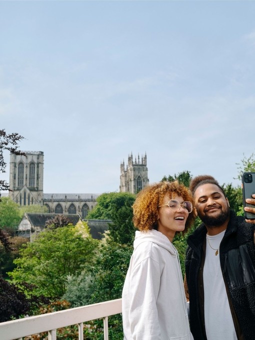 A man and a woman take a selfie in front of a Cathedral view