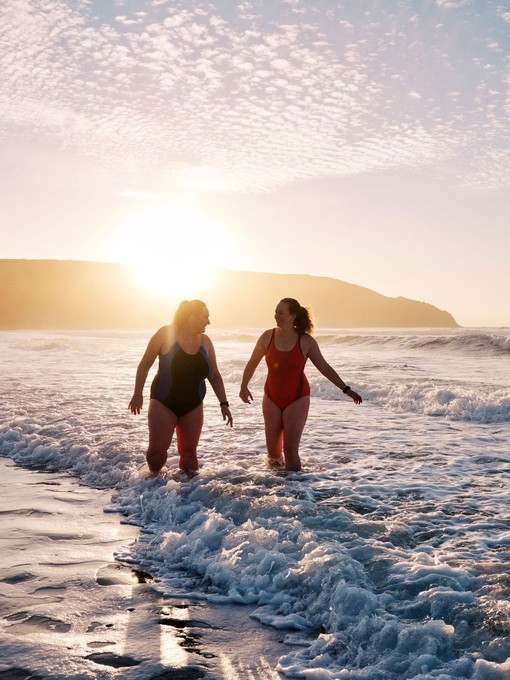 Open water swimmersby the shore at sunset.