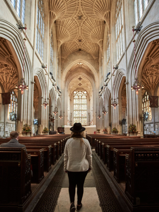 Woman walking down the aisle of an abbey