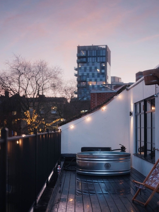 View of two deck chairs and a silver hot tub on the balcony at dusk