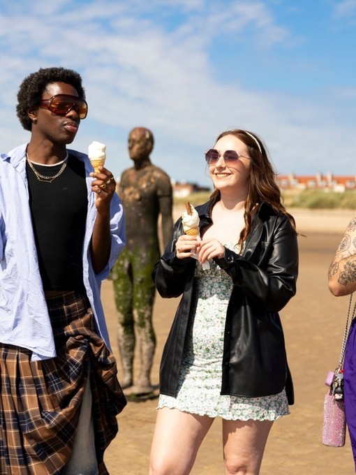 A group of friends walk on the beach with ice creams