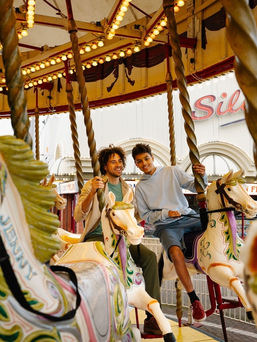 A father and son ride on a Carousel in an amusement park