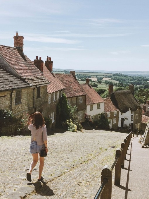 Woman, in shorts, walking down village lane