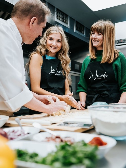 A mother and daughter being shown how to prepare food by a chef