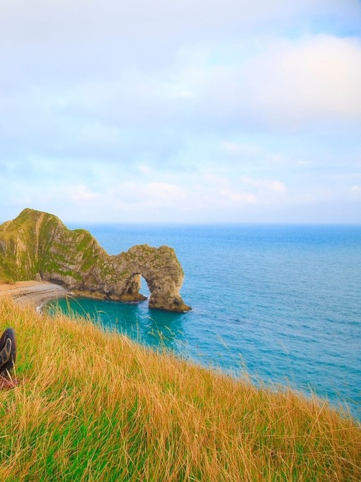 Couple sat on the grass looking out to the sea