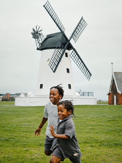 Two young boys having fun on a playing field in front of a windmill