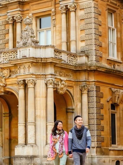 A young, happy couple walking outside a manor