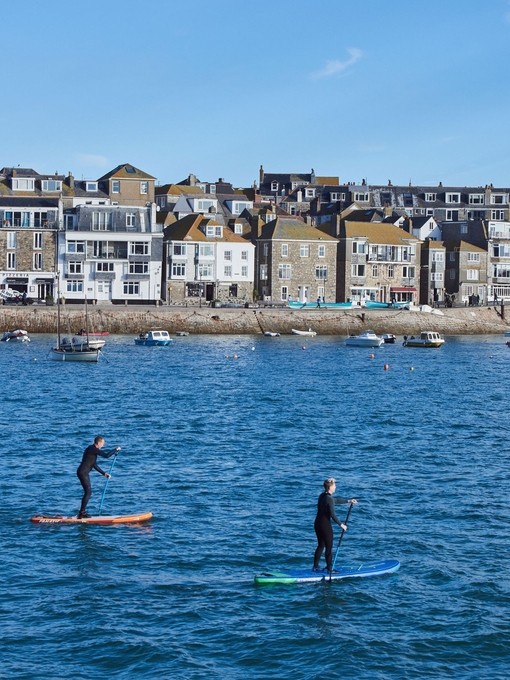 Two people on paddle boards floating in a harbour