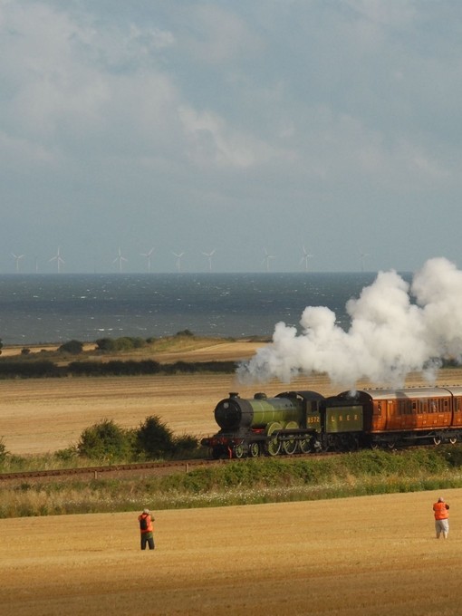 A steam train passing through fields on the coast