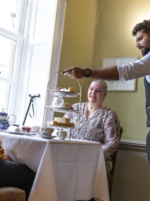 Two women being served afternoon tea by a waiter.