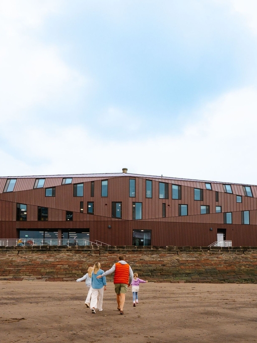 Family having fun on a beach with a modern building in the background