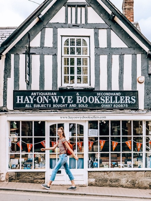 Young woman wearing backpack walks past bookshop