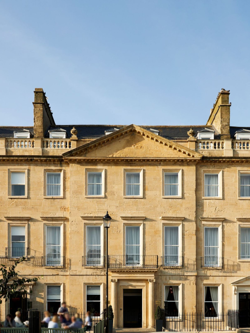 Outside exterior of a large mansion with outside seated courtyard on a clear day.