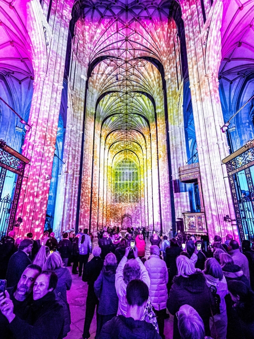 Group of people looking and photographing light show in a cathedral