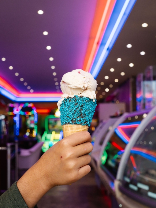A young young boy's hand holds an ice cream at an ice cream parlour
