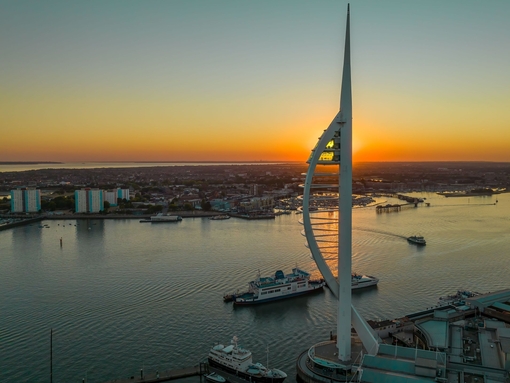 A modern tower next to the ocean at sunset