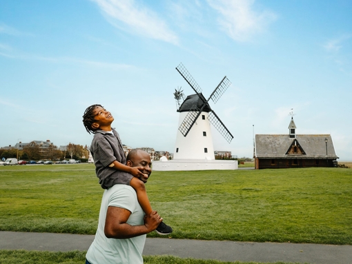A father and son have fun in a field in front of a windmill