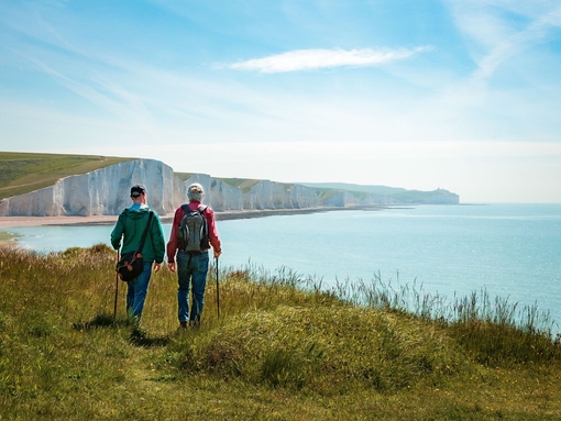 Two men hiking together with the stunning backdrop of white cliffs overlooking the ocean.