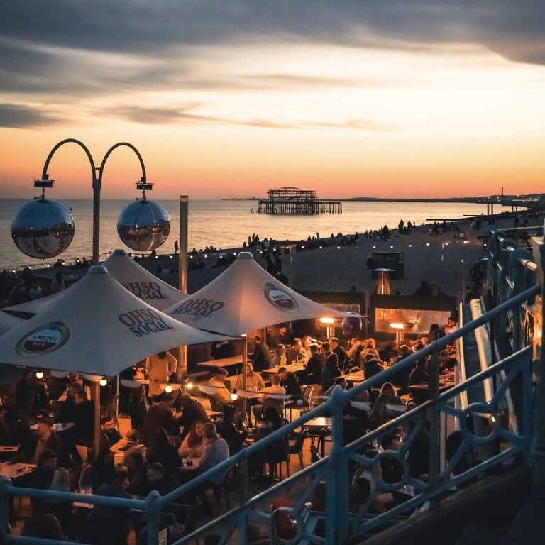 People enjoy drinks at Ohso Social bar on Brighton seafront at sundown