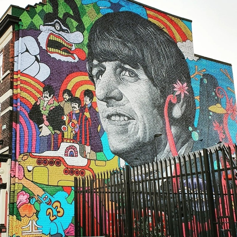 Grafitti art of the Beatles, prominently featuring George Harrison, on a wall in Liverpool