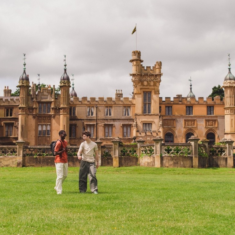 Two young men walk in the grounds of a heritage house