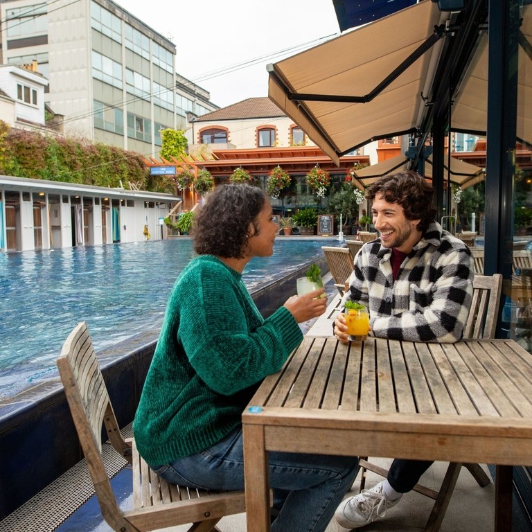 Man and woman enjoy drinks in poolside seating area