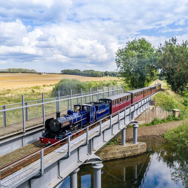 A steam train passing over a river in the Broads National Park