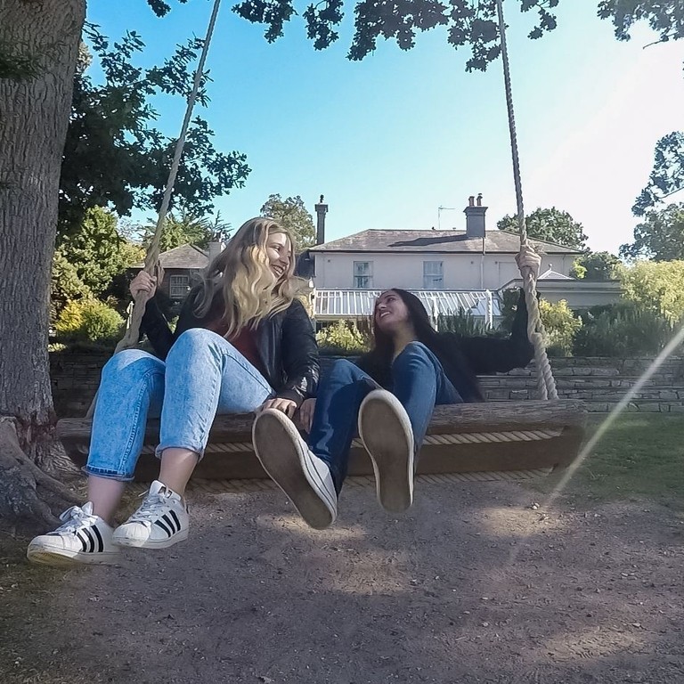 Two women on a swing in a hotel garden