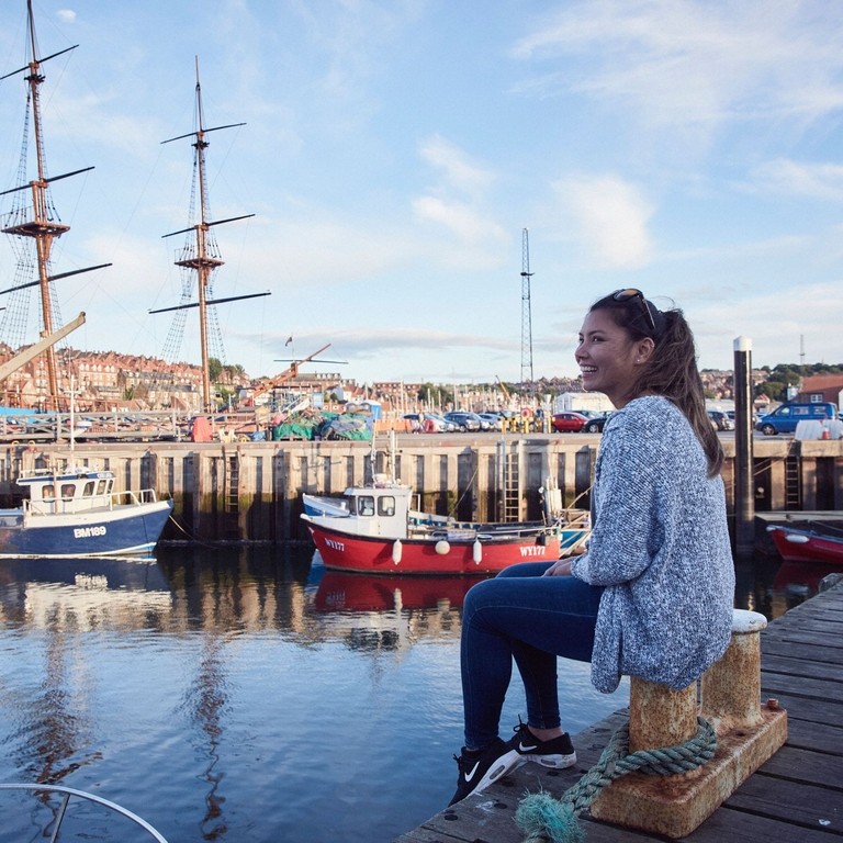 Smiling woman sitting on a jetty in a harbour