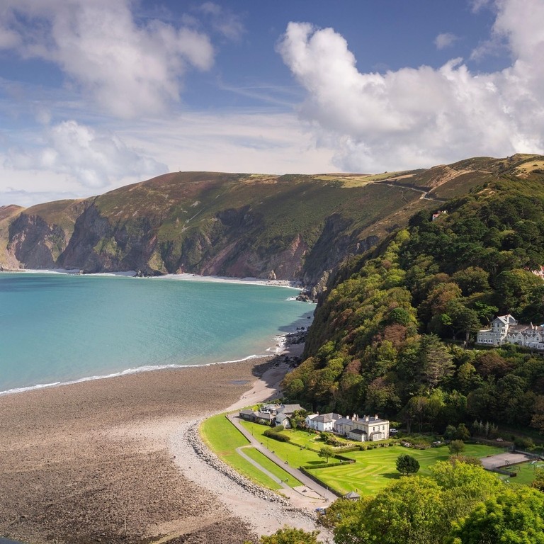 A gorgeous panorama of a turquoise bay with mountains and stately mansions.
