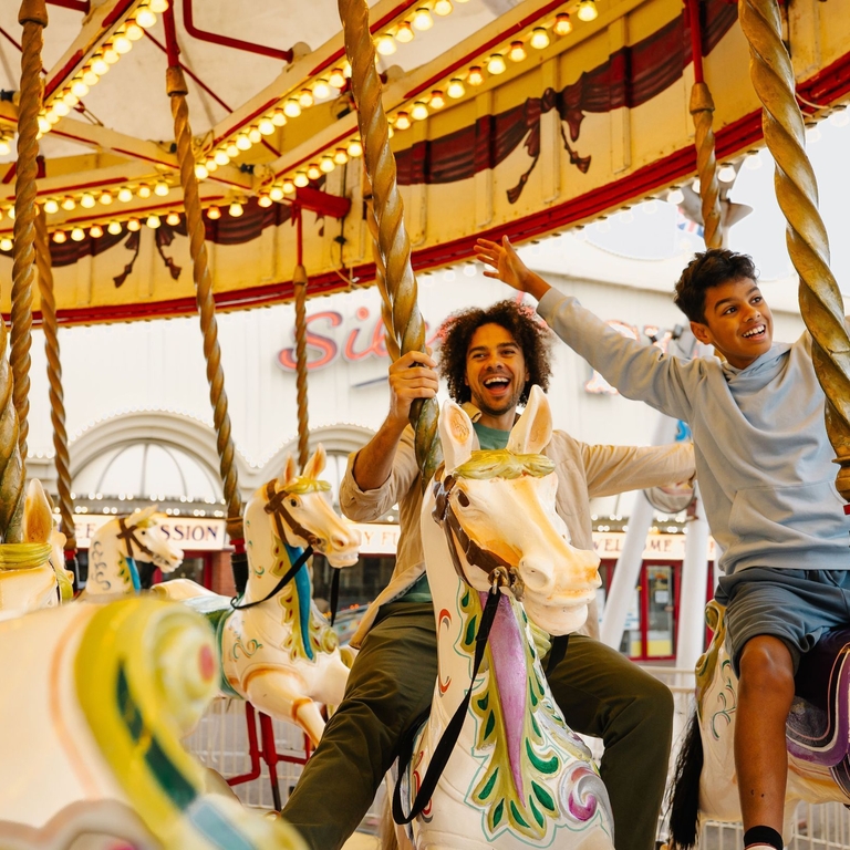 A father and son ride on a Carousel in an amusement park