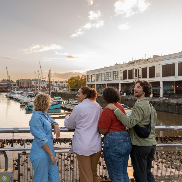 Friends walking over a waterfront bridge.