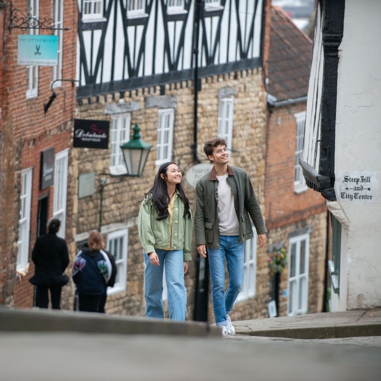 A woman and a man walk up a steep hill in a heritage City