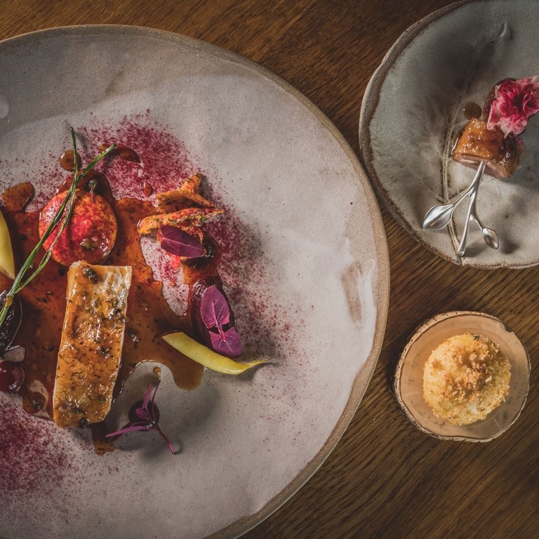 Three different sized plates of colourful food served on rustic grey crockery