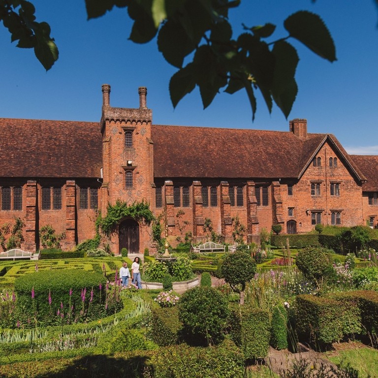 Two women walk through the gardens of a heritage house