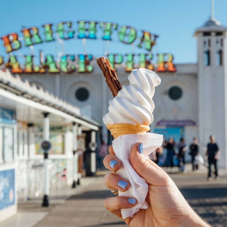 Close up of person holding ice cream cone on pier