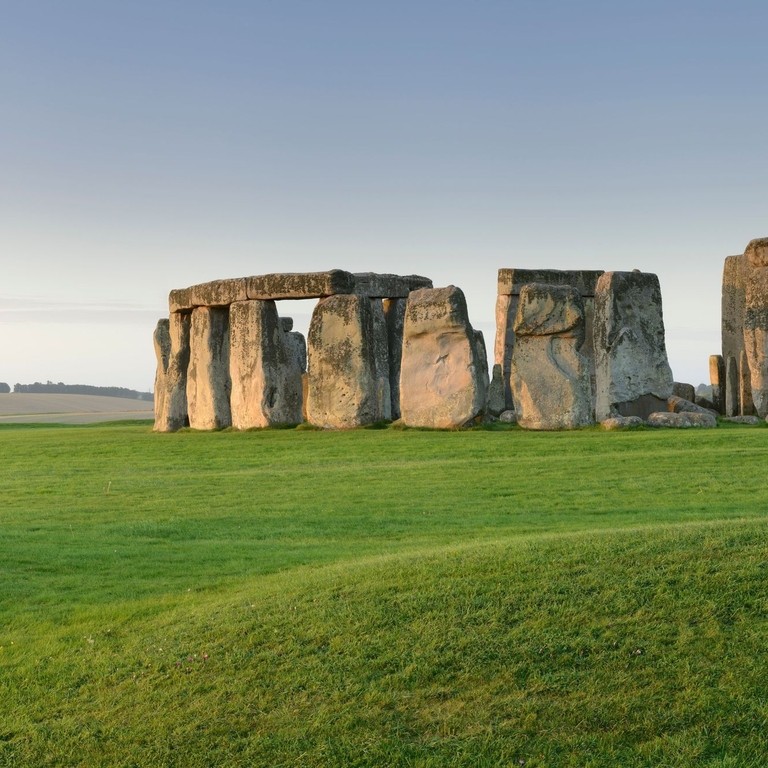 Large stone pillars arranged in circle on grass at sunset