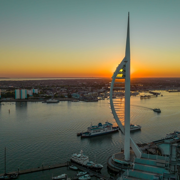 A modern tower next to the ocean at sunset