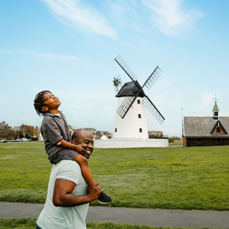 A father and son have fun in a field in front of a windmill