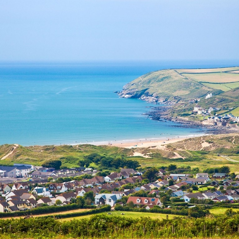 A clear view of a village from above and bay across mountains and out to the ocean