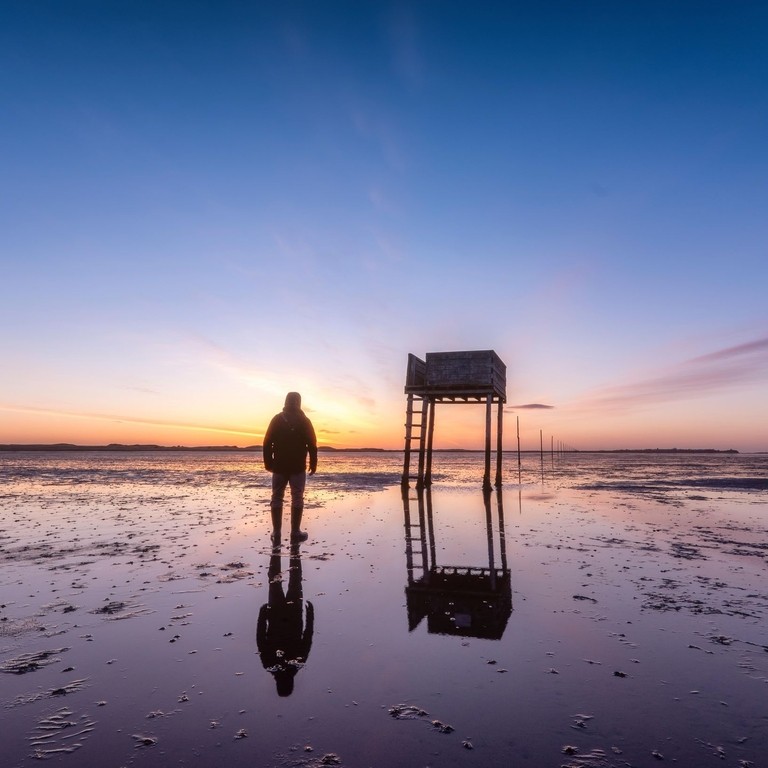 Posts marking the pilgrims' way crossing to Lindisfarne with emergency refuge at sunrise