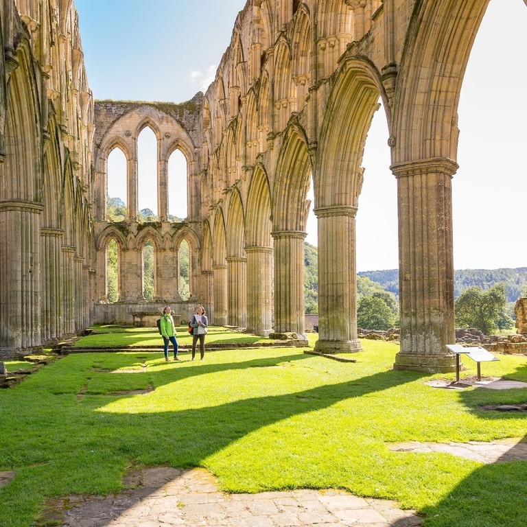 Two female friends in the central nave of a ruined abbey in the sunshine