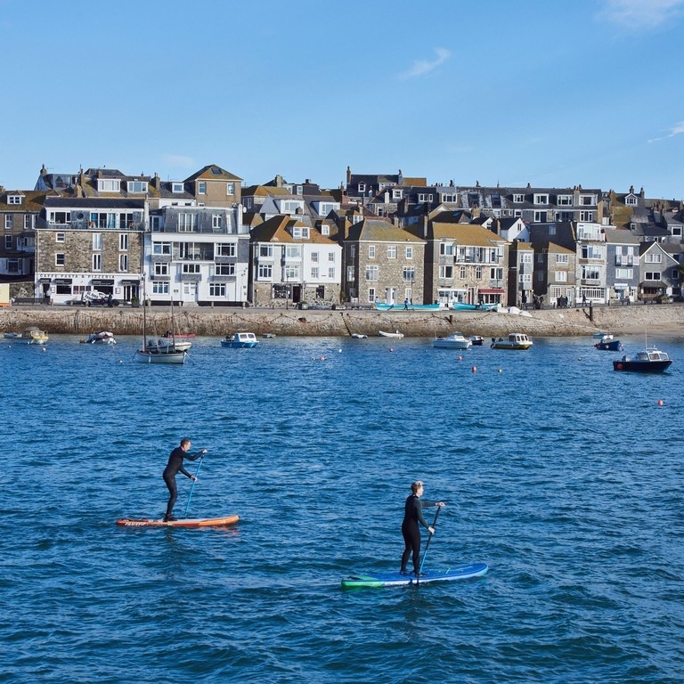 Stand up paddle-boarders in harbour, St. Ives, Cornwall, England.