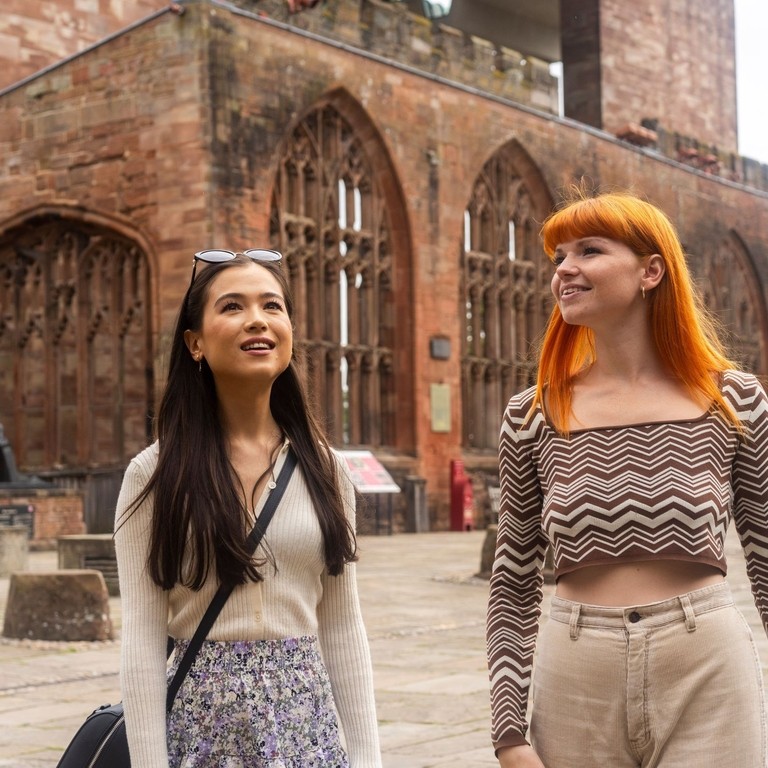 Two women explore the ruins within the grounds of a Cathedral
