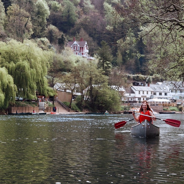 A woman in a canoe with hills and buildings behind